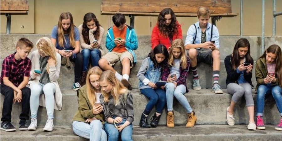 kids looking at each others phones instead of actually having a conversation