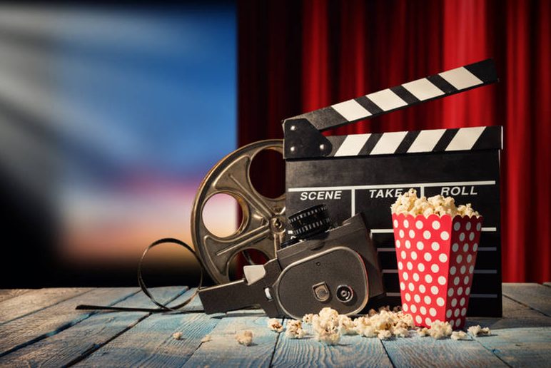 Retro+film+production+accessories+placed+on+wooden+planks.+Concept+of+film-making.+Red+curtain+and+movie+screen+on+background%3B+Shutterstock+ID+594132752